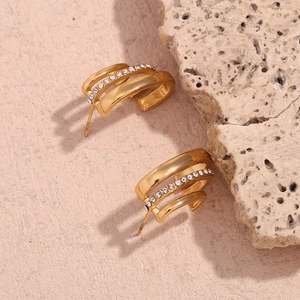 Macro detail of triple-layered C-shaped gold-plated earrings with sparkling crystals