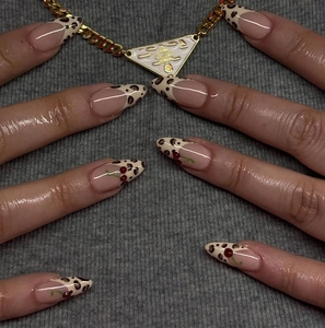 Detail of almond-shaped French nails with leopard print and red cherry accents