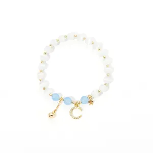 Detail of beaded bracelet with white cat-eye stones, blue beads and gold moon star charms