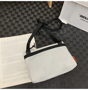 Detailed view of white nylon messenger bag with black strap on minimalist magazine background