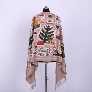 Detail of soft beige Christmas scarf featuring holiday trees, foxes and festive tassels
