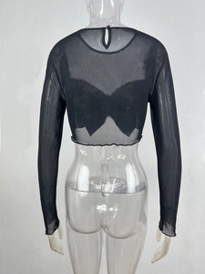 Détail du crop top en maille noire avec un grand nœud décoratif au dos du vêtement