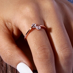 Close-up of a rose gold heart ring with small clear gems worn on a finger