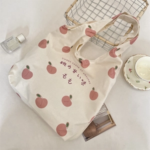 Detailed close-up of a peach print canvas tote bag with a metal snap button closure
