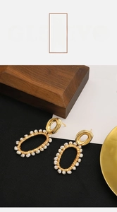 Macro detail of handmade gold wire oval earrings decorated with white natural pearls