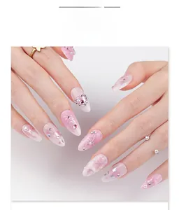 Macro view of almond shaped fake nails with pink bow and sparkling rhinestones