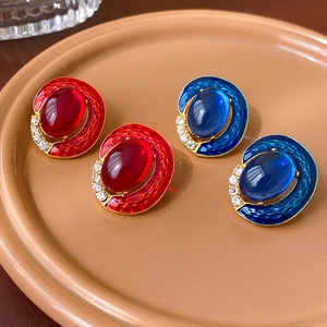 Detail of vintage gold earrings with oval red and blue gemstones and small diamonds
