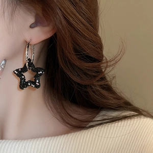 Gros plan de boucles d'oreilles étoile noire scintillantes portées par un mannequin