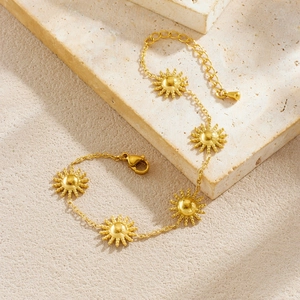Elegant gold plated stainless steel sun charm bracelet on a textured stone surface