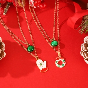 Juego de collares navideños con colgantes de guantes y corona sobre fondo rojo festivo
