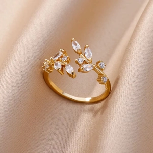 Detailed close-up of 18K gold-plated leaf ring with sparkling zircon on silk background