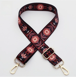 Close-up of ethnic floral embroidery on a wide shoulder strap with gold metal hooks