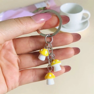 Detail showing colorful resin mushroom charms on a metal keychain held by a hand