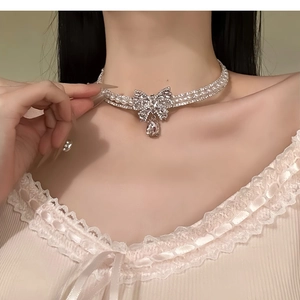 Detailed view of rhinestone bow necklace with pearl chains and teardrop crystal pendant