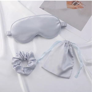 Flat lay of light blue satin sleep set including an eye mask, scrunchie, and storage bag