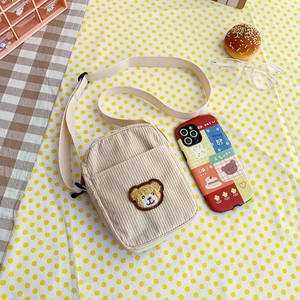 Cute beige corduroy crossbody bag for kids featuring a bear embroidery and adjustable strap