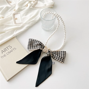 Detail of pearl headband with houndstooth bow and golden buckle on aesthetic background