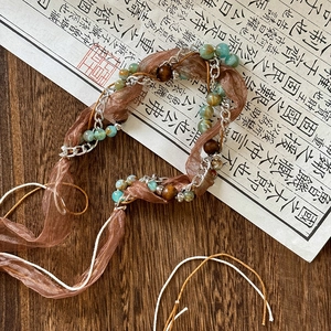 Detail of bohemian braided waist chain with turquoise beads on vintage wood surface