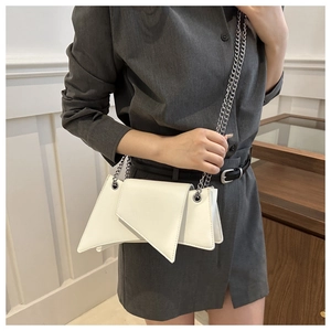 Close-up of white asymmetric underarm bag with silver chain strap worn by a model