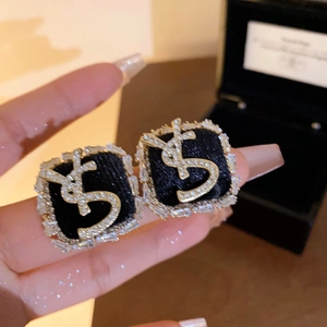 Detail of gold YSL logo earrings with black velvet inlay and sparkling zircon crystals