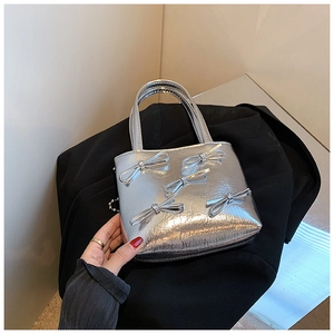 Silver handbag with pleated texture and decorative bows shown in a hand-held detail view