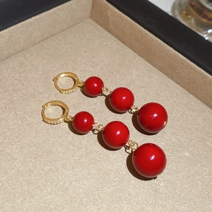 Detail of red resin triple bead drop earrings with gold plated zircon studded hoop