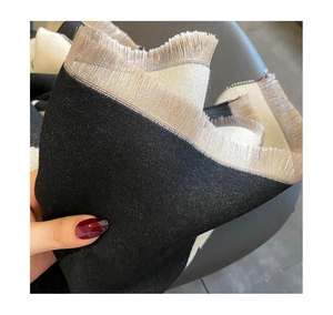 Détail rapproché de l'écharpe bicolore avec texture tricotée et franges en noir et beige
