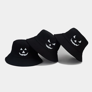 Detailed view of black cotton bucket hats with white Halloween pumpkin face prints