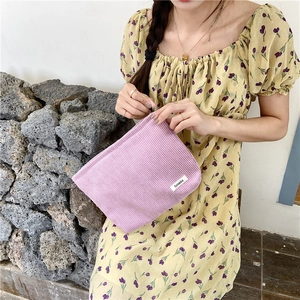 Close-up of lavender corduroy pouch held by a model in a floral dress for daily use