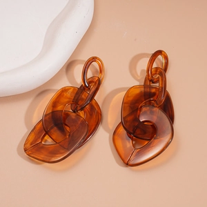 Detailed view of amber acrylic chain link earrings with glossy resin texture on beige base
