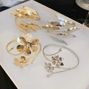 Detailed view of layered floral and leaf cuffs in gold and silver with rhinestone accents