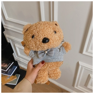 Close-up of brown plush bear crossbody bag with a grey sweater and pearl bow tie detail