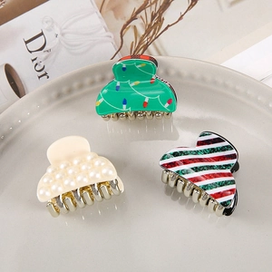 Detailed close-up of three Christmas acrylic hair claws with festive patterns and gold teeth