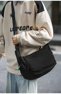 Detail of waterproof black nylon messenger bag featuring adjustable green zipper pulls
