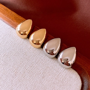 Macro view of teardrop metal earrings in gold and silver with a polished mirror finish
