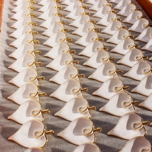 White enamel calla lily earrings with gold edges arranged in a professional batch display