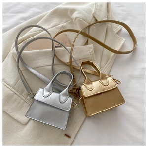Flache Liegeansicht kleiner Taschen in Silber und Gold mit einem beigen Damenblazer