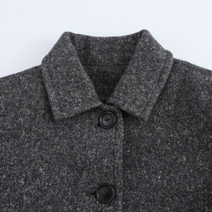 Detail shot of the notch lapel and black buttons on a charcoal wool blend coat