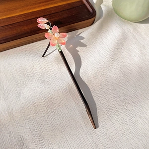 Detail of oriental style wooden hair pin with pink petals and delicate pearl accents