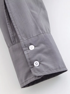 Close-up of grey shirt cuff with dual white button detail and smooth fabric texture