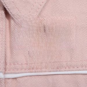 Macro detail of three heart enamel pins with diverse slogans on pink denim background