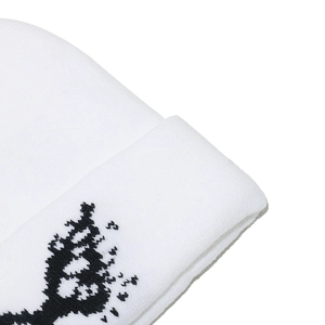 Close-up of white knit beanie showing black butterfly jacquard pattern and ribbed texture