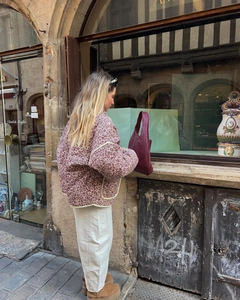 Outdoor street view of floral quilted jacket paired with a woven leather tote bag