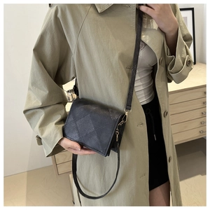 Detail of grey quilted crossbody bag showing fine stitching and gold-tone metal hardware