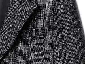 Vista dettagliata del tessuto tweed a spina di pesce sul bavero con cuciture precise