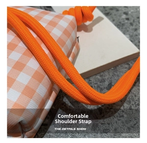 Close-up of orange gingham fabric bag featuring a thick braided rope shoulder strap