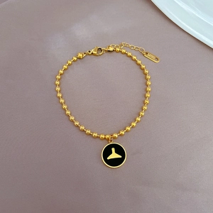 Détail du bracelet en acier inoxydable doré avec un pendentif rond en émail noir