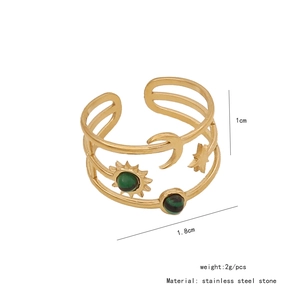 Detailed macro view of gold sun ring with green stone and engraved celestial patterns