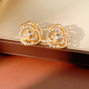 Close-up of elegant gold hollow rose earrings with sparkling crystals in a gift box