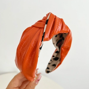 Detail of orange knotted PU leather headband featuring a stylish leopard print lining